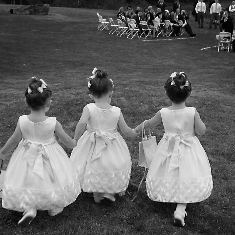 Black and white image of three girls running in an open field