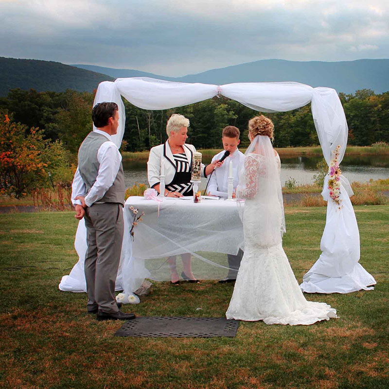 A bride and a groom standing near a table in a field