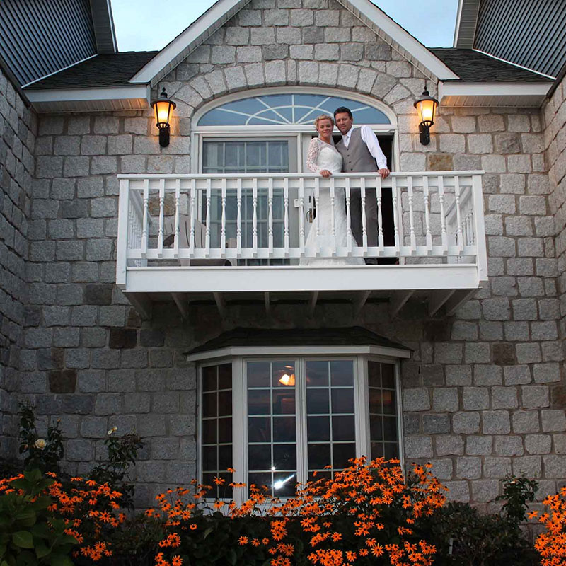 A bride and a groom standing at a balcony of a house