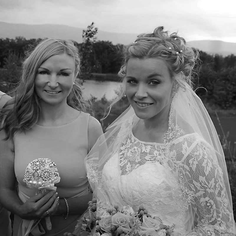 Black and white image of a bride standing with her friend