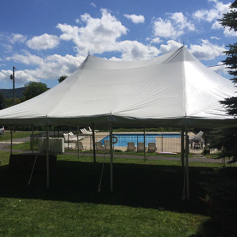 Outside view of a field with a white tent placed in it for wedding
