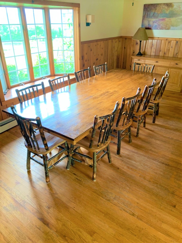 A dining room with a large wooden table and chairs.