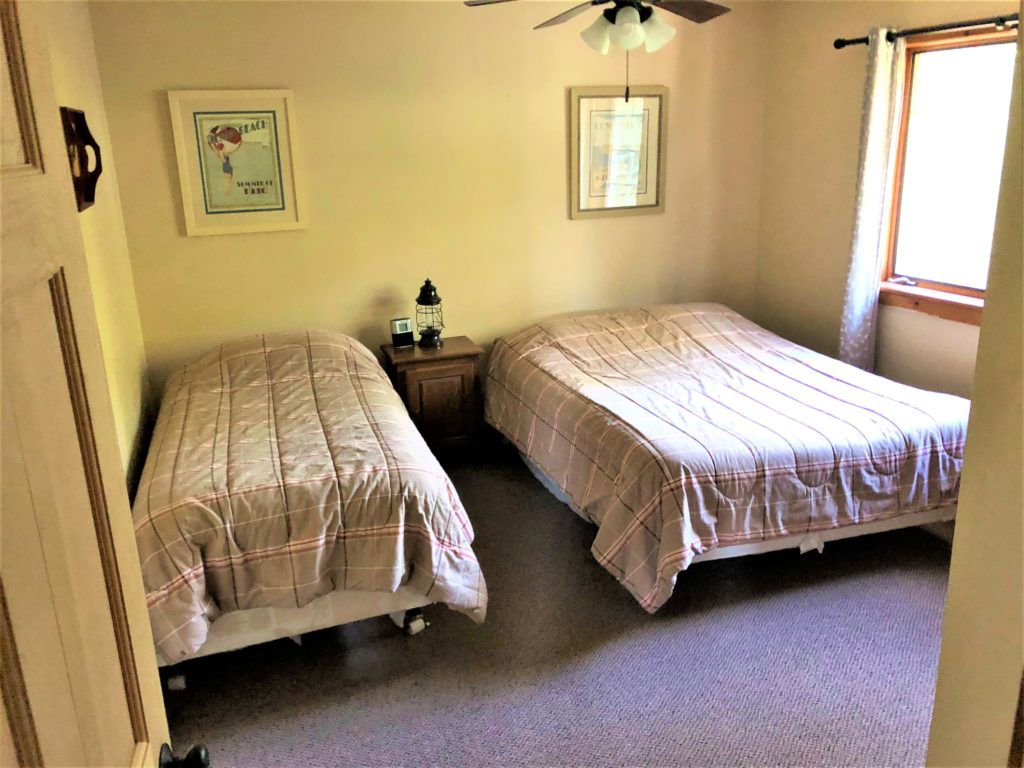 Two beds in a room with a ceiling fan.