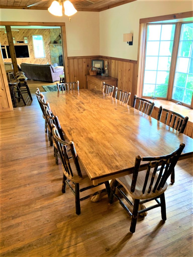 A dining room with a large wooden table and chairs.