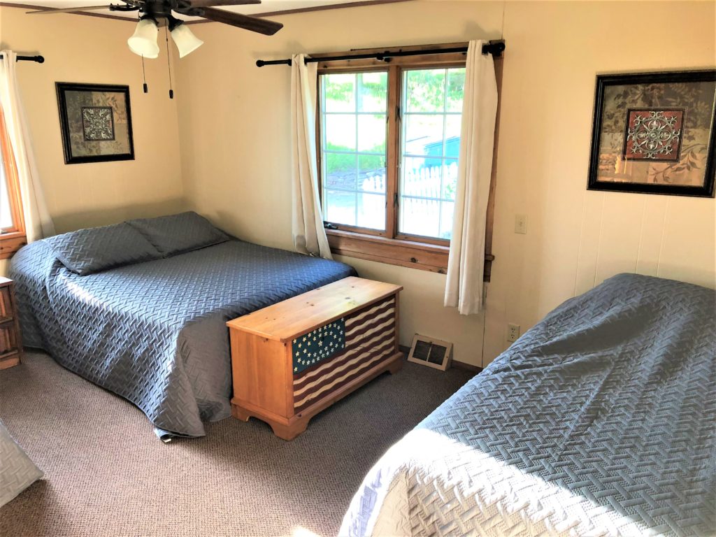 Two beds in a room with a ceiling fan.