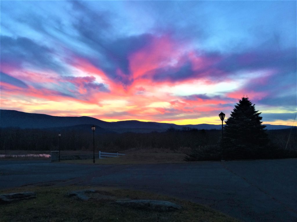 A colorful sunset over a parking lot with mountains in the background.
