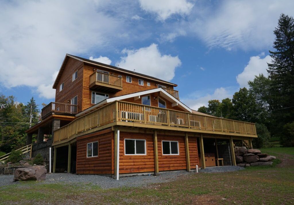 A large log cabin with a deck on the side.