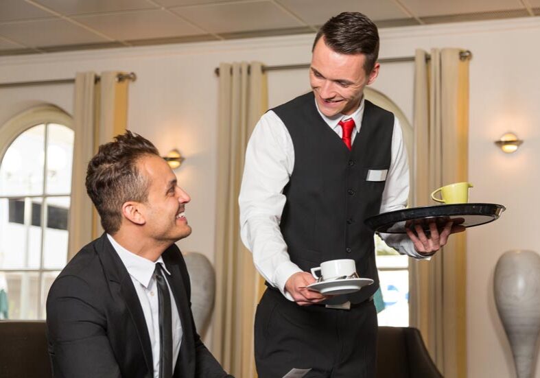 A waiter serving a man in a restaurant.