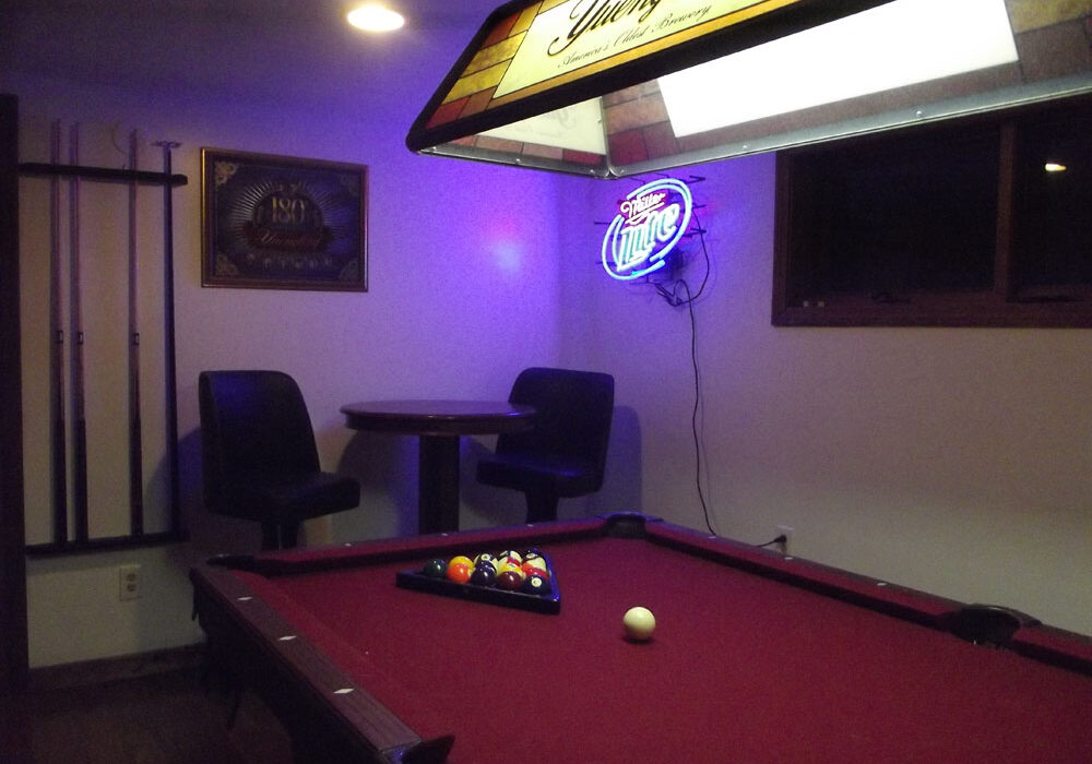 A pool table in a room with a neon light.