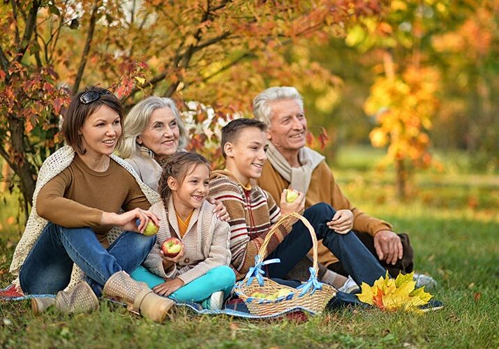 A family sitting on the grass in an autumn park.